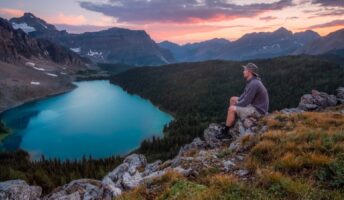 man looking on mountain sitting on rock