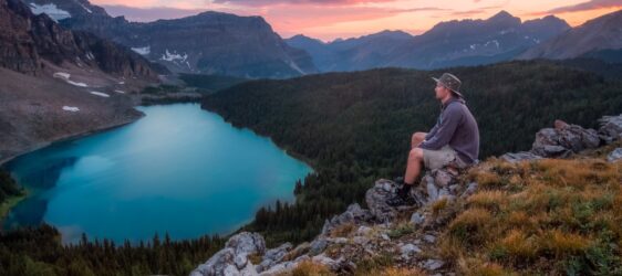 man looking on mountain sitting on rock